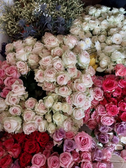 A vibrant display of fresh floral arrangements featuring predominantly roses in shades of pink, white, and cream. The roses are tightly clustered, showcasing their lush petals and delicate textures, w